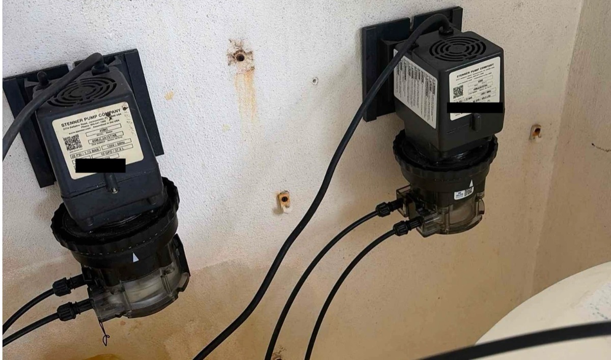 Two Stenner peristaltic pumps mounted in a commercial pool equipment room
