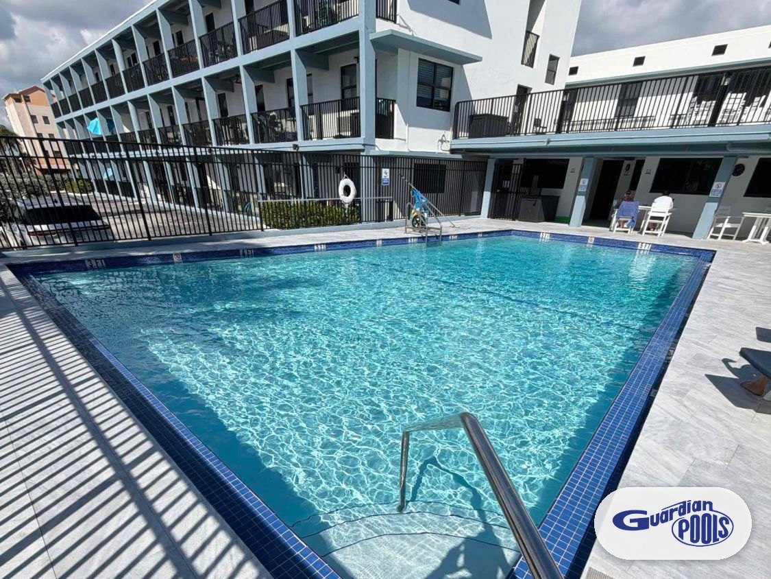 Finished beachside condominium pool in Hollywood with a blue tile border, stainless handrail, and light stone deck
